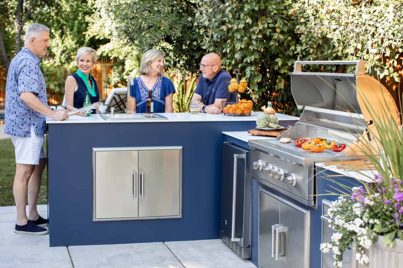 group of friends gathered around modern outdoor kitchen