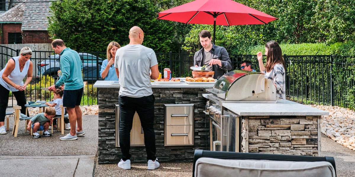 group of people grilling a meal at an outdoor kitchen bar