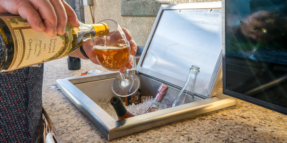 man pouring wine over drop in cooler for outdoor kitchen