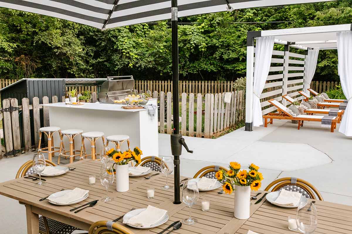 modern boho style backyard with dining table outdoor kitchen and pergola with curtains