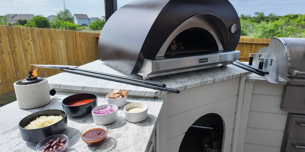 outdoor pizza oven with pizza toppings on countertop