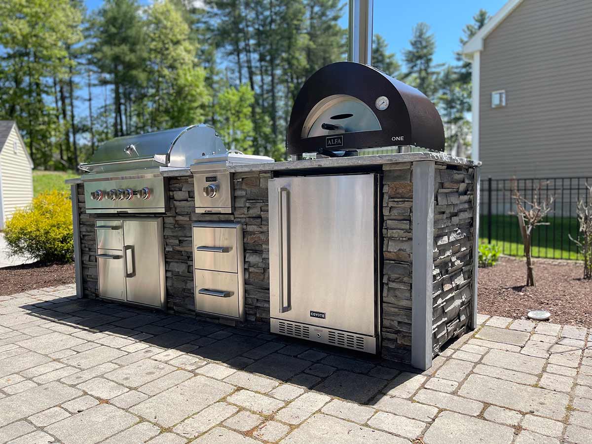 stacked stone outdoor kitchen with gas grill side burner and pizza oven